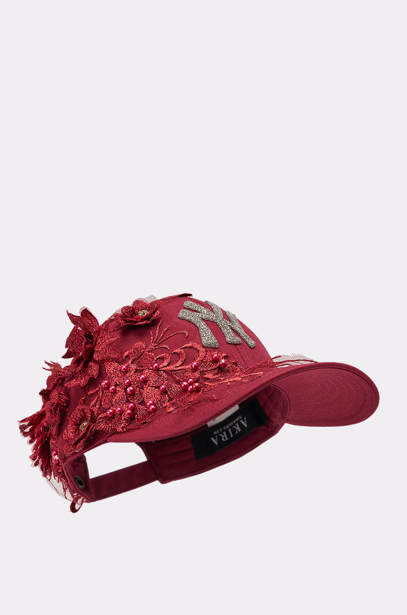 The FROM YA CITY APPLIQUE HAT is a red baseball cap with silver "NY" applique on the front, intricate floral embroidery with beads and lace on the side, plus an adjustable strap and inner "AKILA" label. 3