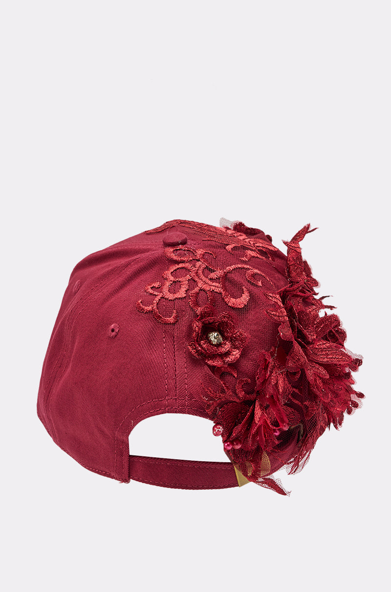 The FROM YA CITY APPLIQUE HAT is a maroon statement piece with intricate lace embroidery and red fabric flowers on one side, plus a back opening and adjustable strap for a perfect fit. 4
