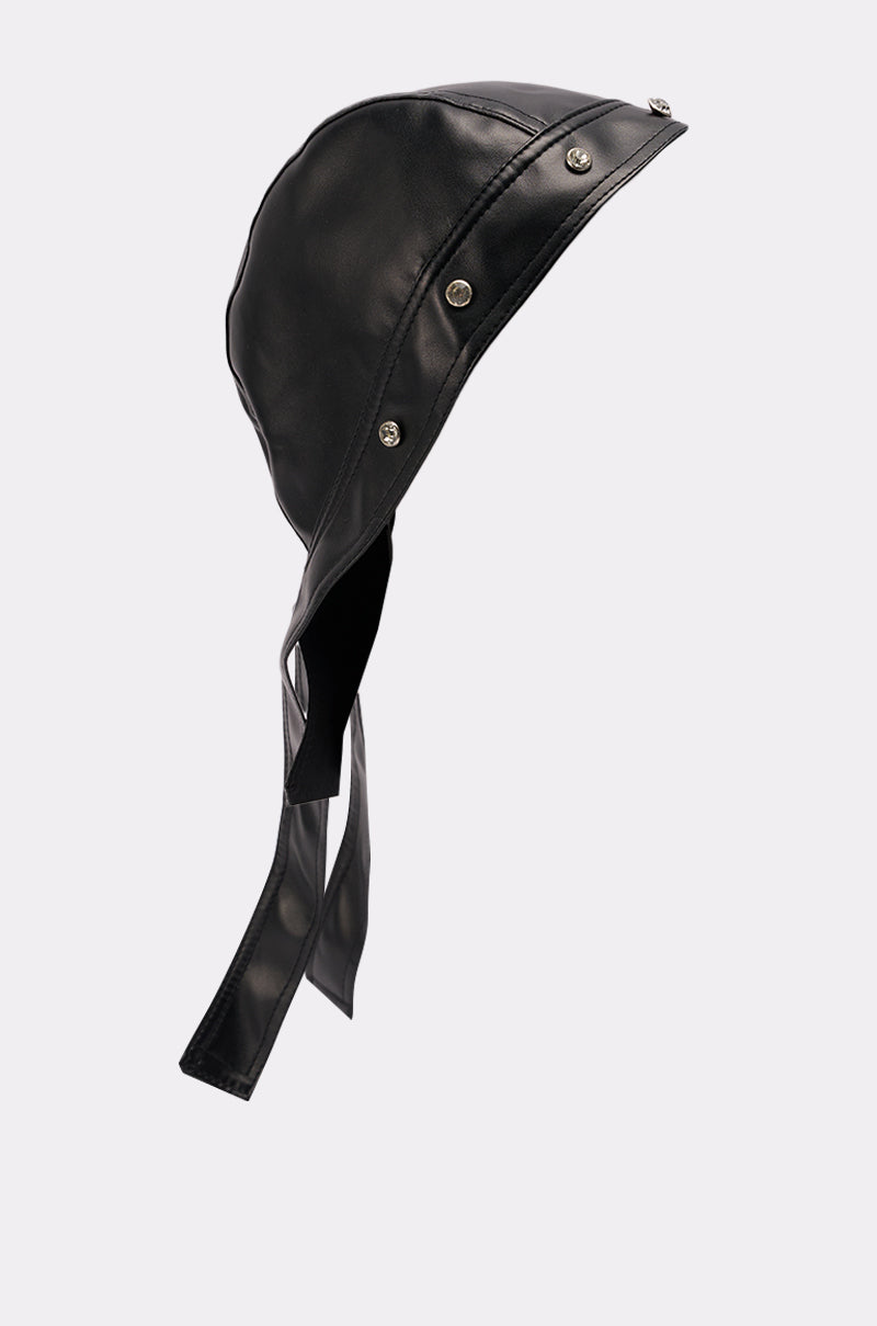 The CASEY PU TIE SKULL CAP is a black faux leather aviator-style hat with a smooth finish, metal snap buttons, and two long straps, displayed on a plain light gray background. 4