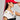 A woman wearing the BIGGER IS BETTER BOW SNAPBACK in red, paired with large hoop earrings and a white top featuring a black design. Her top is adorned with a small badge and the text "2024." She stands sideways, adjusting her bow snapback with her hand.