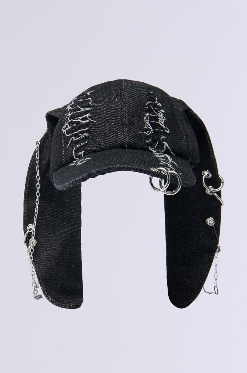 The AERIAL VIEWS HAT is a black denim baseball cap featuring distressed patches and metallic silver accessories. It stands out with metal chains draped over the sides and is embellished with rings and piercings on a simple light gray background. 2