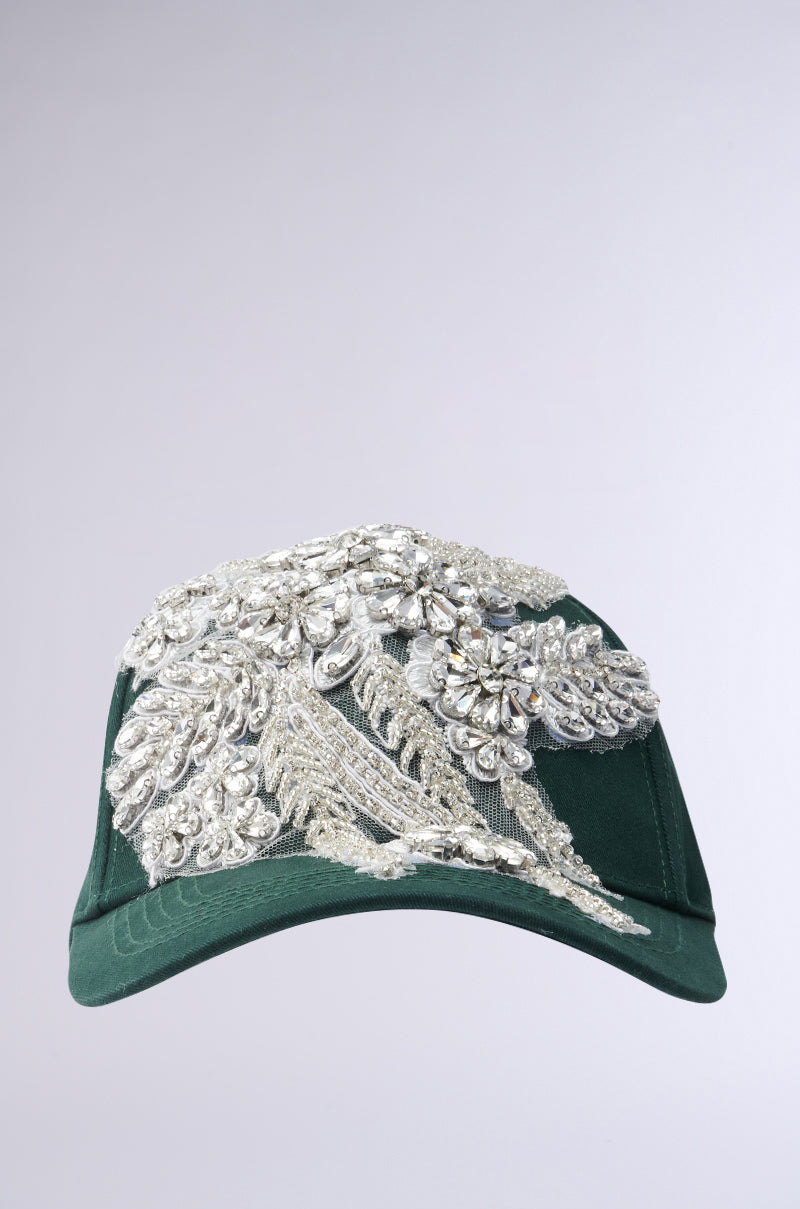 The FOREVER EXTRA APPLIQUE HAT from AKIRA Label is a green baseball cap featuring intricate silver beading and embroidery with floral and abstract designs, reminiscent of rhinestone embellishment, on a plain gray background. 3