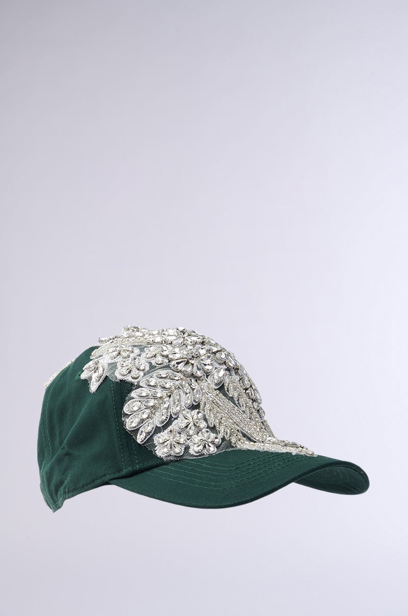 The FOREVER EXTRA APPLIQUE HAT from the AKIRA Label features intricate silver bead and crystal embellishments on a dark green base, creating a rhinestone-like pattern on the front against a light gray gradient background. 4
