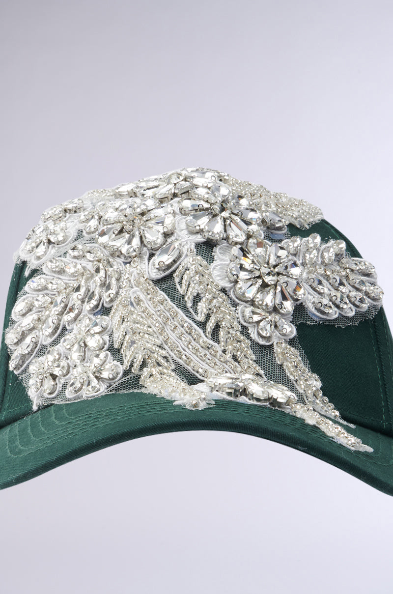 The FOREVER EXTRA APPLIQUE HAT by AKIRA Label is a green baseball cap featuring detailed silver and clear sequin floral appliques, adding elegance to its casual look against a neutral gray backdrop. 5