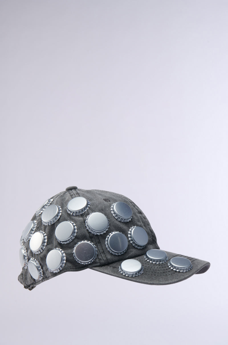 The BOTTLES ON ME HAT from AKIRA Label is a gray baseball cap featuring large shiny silver bottle cap embellishments on the front, top, and brim, displayed against a plain light gray background.