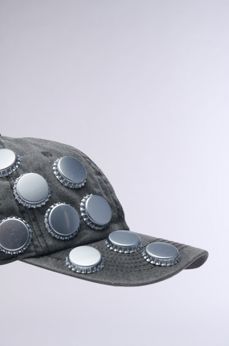 The BOTTLES ON ME HAT is a gray AKIRA Label baseball cap featuring bold bottle cap embellishments on the front and brim, shown against a light background.