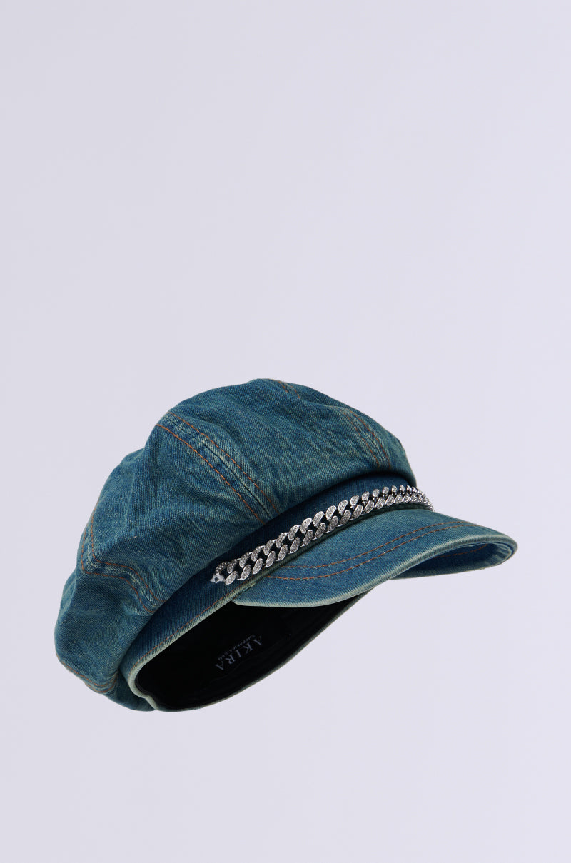 The Denim Blues Brim Hat is a blue denim Newsboy cap adorned with a rhinestone-embellished chain along the front of the brim, set against a light grey background. 4