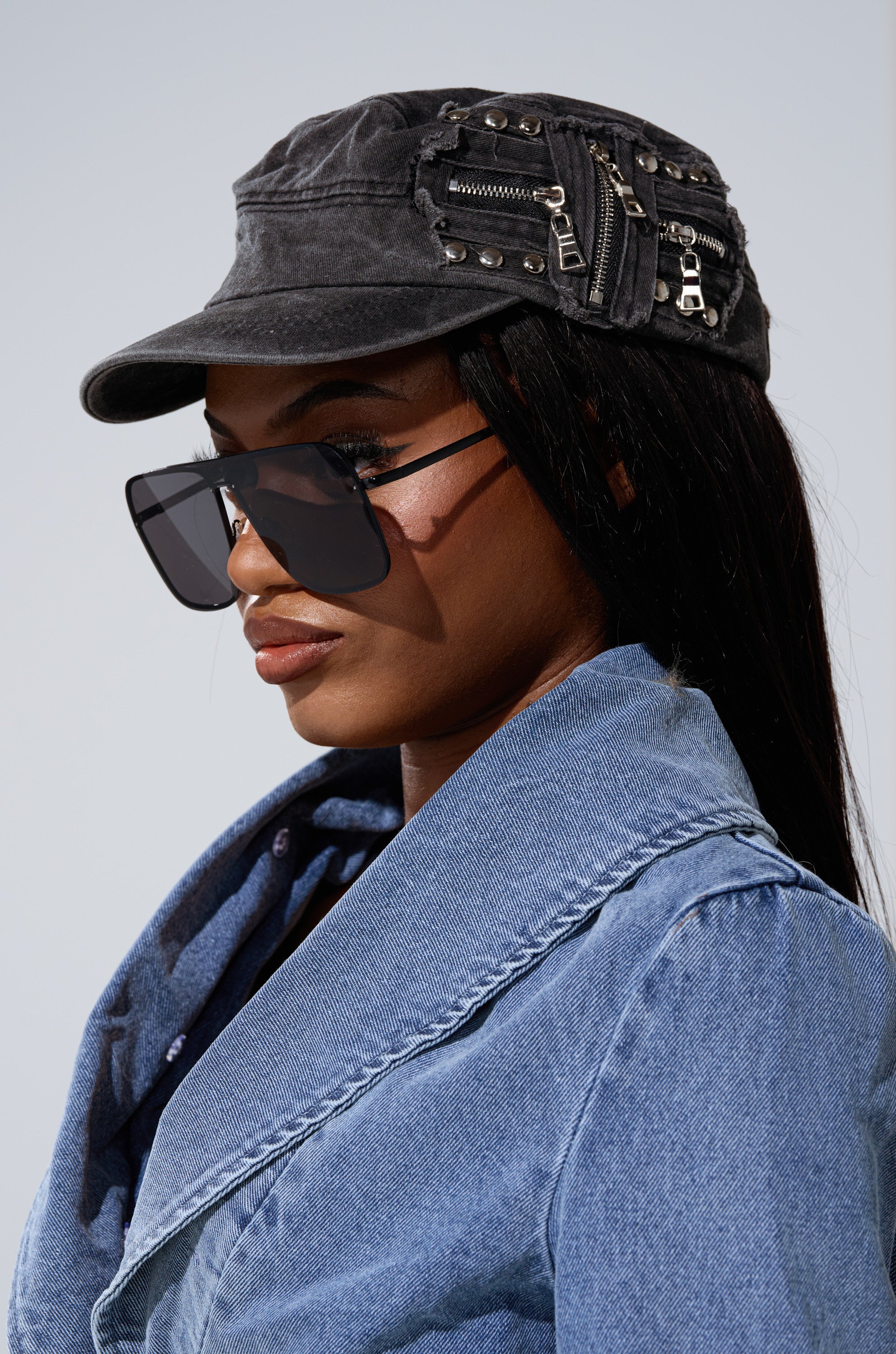 A woman wears the I REALLY DO THIS HAT, large black sunglasses, and a denim jacket, looking to the side against a neutral background. 1