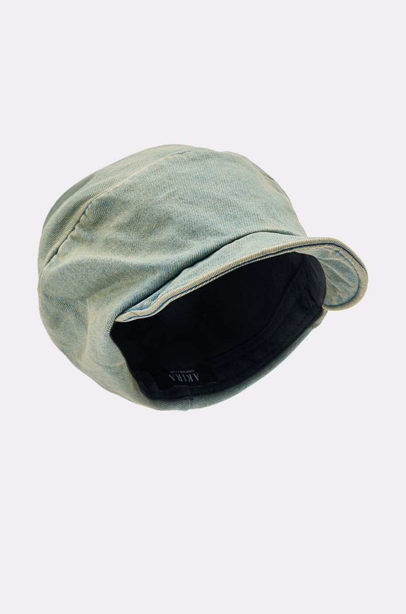 The IT GURL SLOUCH DENIM HAT is a light green denim bucket hat featuring a wide, slightly curved brim and a visible black inner lining, shown against a plain light gray background.