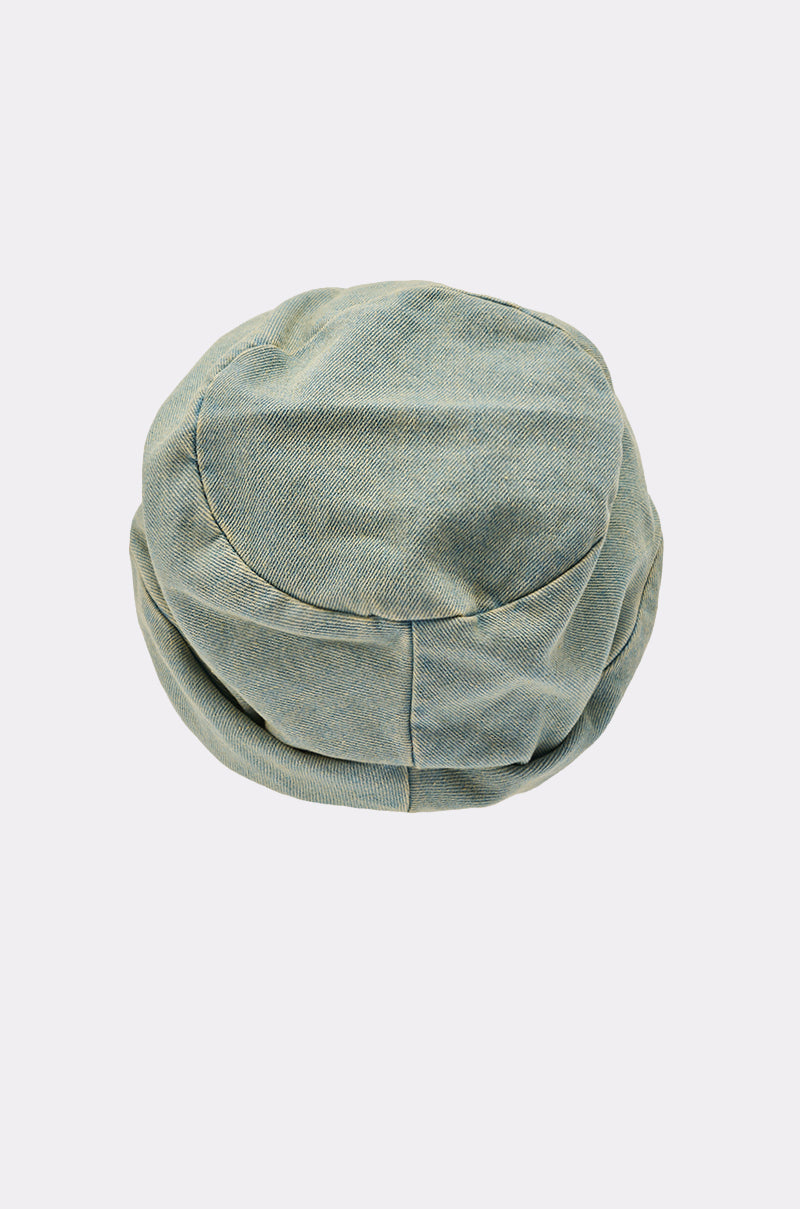 The IT GURL SLOUCH DENIM HAT features a light green, round, flat-topped cap made from denim-like fabric, displayed from above on a plain light background.