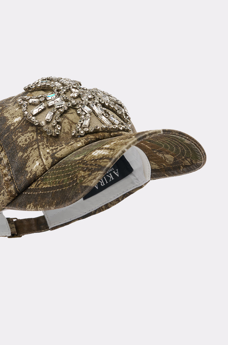 The SEE ME APPLIQUE HAT is a camo baseball cap with bold silver beaded detailing on the front and an adjustable back strap—a standout street style accessory by AKIRA. 6