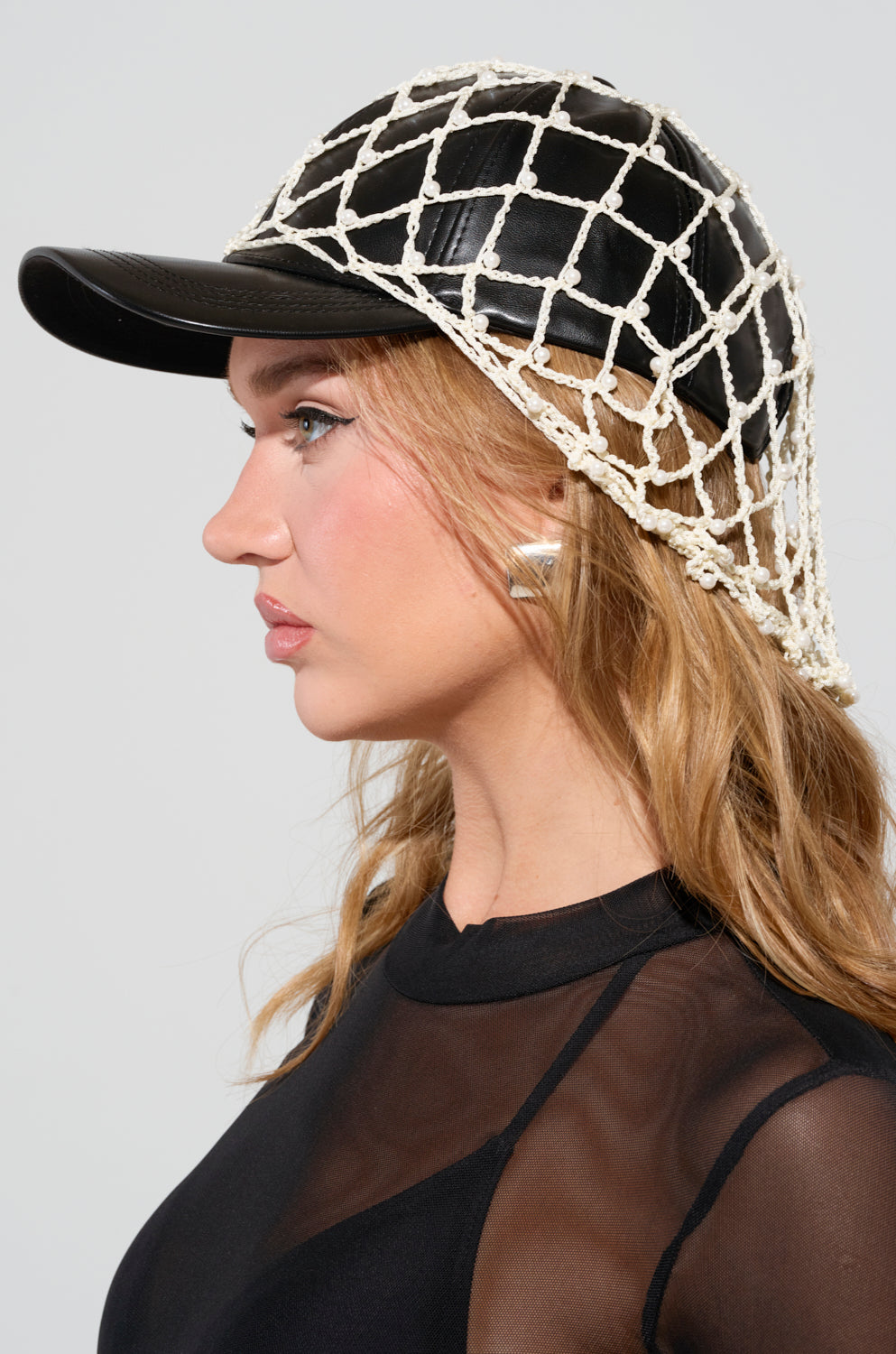 A woman in a black mesh top and silver earrings, facing left, wears the "CATCH ME IF YOU CAN HAT," featuring a faux leather cap with a white rope fishnet overlay. 0