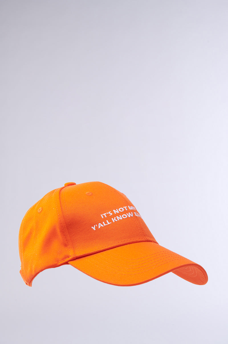 The ITS NOT HAT is an orange baseball cap with a curved brim, featuring the white embroidered text "IT’S NOT ME, Y’ALL KNOW GOD" on the front, shown against a plain light gray background.