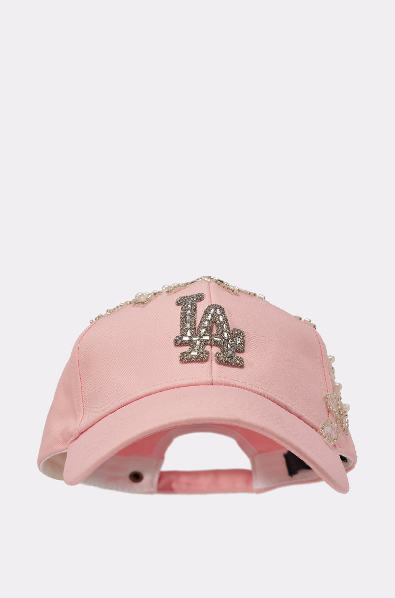 THE CITY APPLIQUE HAT: A light pink, feminine baseball cap with a sparkly silver "LA" logo, embellished with decorative pearls and rhinestones—ideal for adding glam to your look. 2