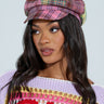 A woman wears the UR STYLE ICON Plaid Brim Hat in pink and yellow, perfectly matching her purple knit sweater with colorful crochet. Her long wavy hair cascades as she gazes slightly right against a white backdrop, exuding a hint of Y2K accessory charm.