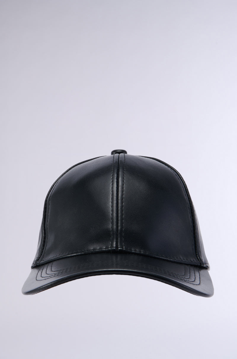 The PU SNAPBACK baseball cap, made from black faux leather, showcases visible stitching details along the seams and brim, all set against a plain grey background. 2