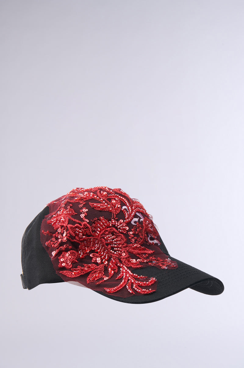 The IN MY CITY APPLIQUE HAT is a black baseball cap featuring detailed red floral beaded embroidery, shown on a plain light gray background.