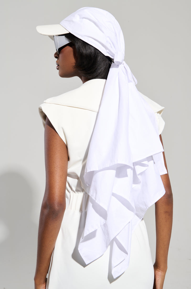 A person is wearing a white headscarf and the TIE IT ALL BACK PU HAT, complemented by large sunglasses, in a sleeveless white outfit, facing away from the camera against a plain light gray background.