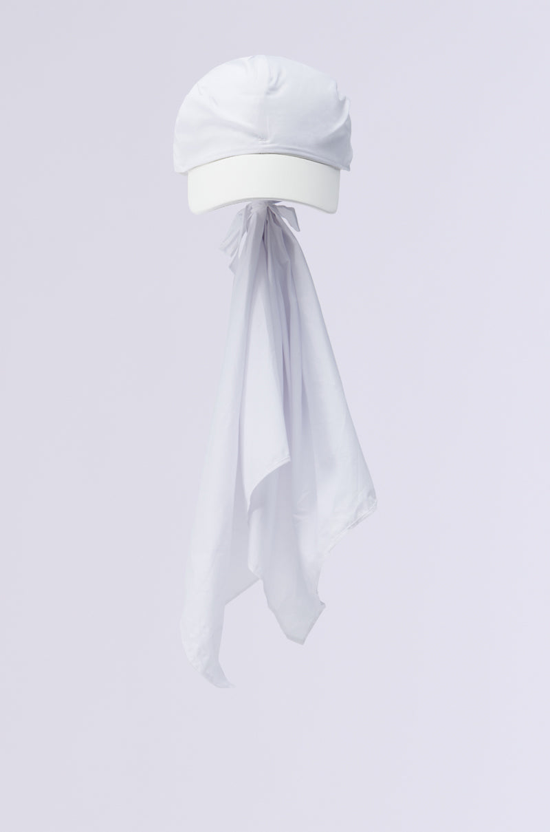 The TIE IT ALL BACK PU HAT, crafted from white faux leather, features an elegantly attached long neck flap that gracefully hangs against a plain light background, embodying AKIRA Label’s distinctive design flair.