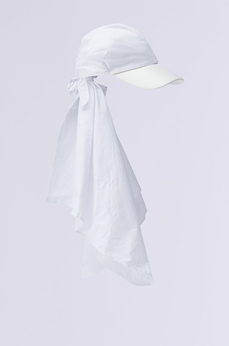 The TIE IT ALL BACK PU HAT from the AKIRA Label is a white baseball cap with an elongated fabric extension that drapes gracefully along the back and sides, offering sun protection. It includes a visor to shield the face, and its fabric is stylishly tied at the back, forming a sleek silhouette against a simple backdrop.