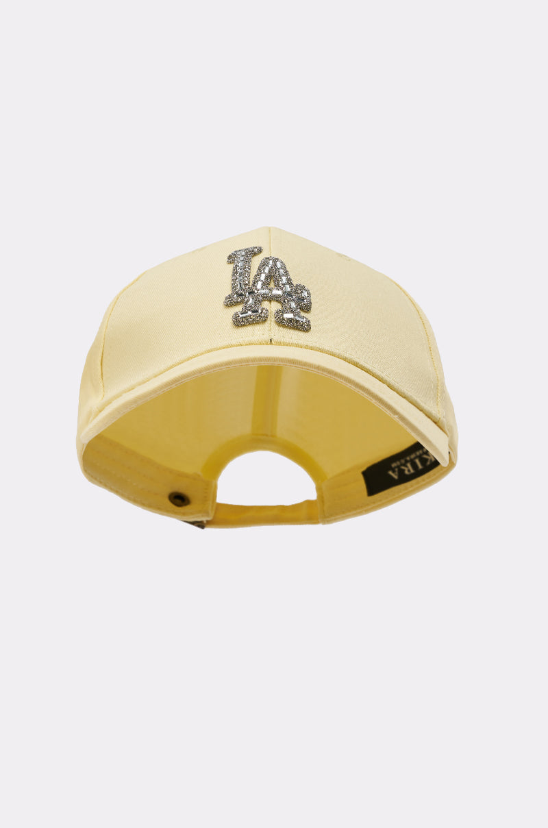 The IN THE SUN BLING HAT features a light yellow rhinestoned design, a sparkling "LA" logo front, and an adjustable back strap—perfect for adding shine to your streetwear, shown here from the rear. 4