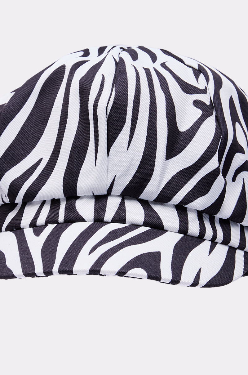 A close-up of the ZEBRA LUXE BRIM HAT highlights its striking black and white pattern set against a plain, light background.