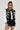 Wearing sunglasses and the eye-catching DRAGONETTE EMBELLISHED BOMBER adorned with dragon embroidery and shimmering accents, a person with long braided hair teams it with a leather mini skirt. They pose confidently against a neutral background, effortlessly radiating coolness.