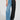 A person wearing the distinctive Extreme Stretch Patchwork Wide Leg Jeans makes a bold fashion statement by combining one side with light blue denim and the other with black leather-like material, perfectly paired with black shoes and a graphic T-shirt.