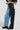 A person is wearing the EXTREME STRETCH PATCHWORK WIDE LEG JEANS, showcasing a bold design with one leg in light blue stretch denim and the other in black fabric. They complete this striking ensemble with black platform boots for a standout look.