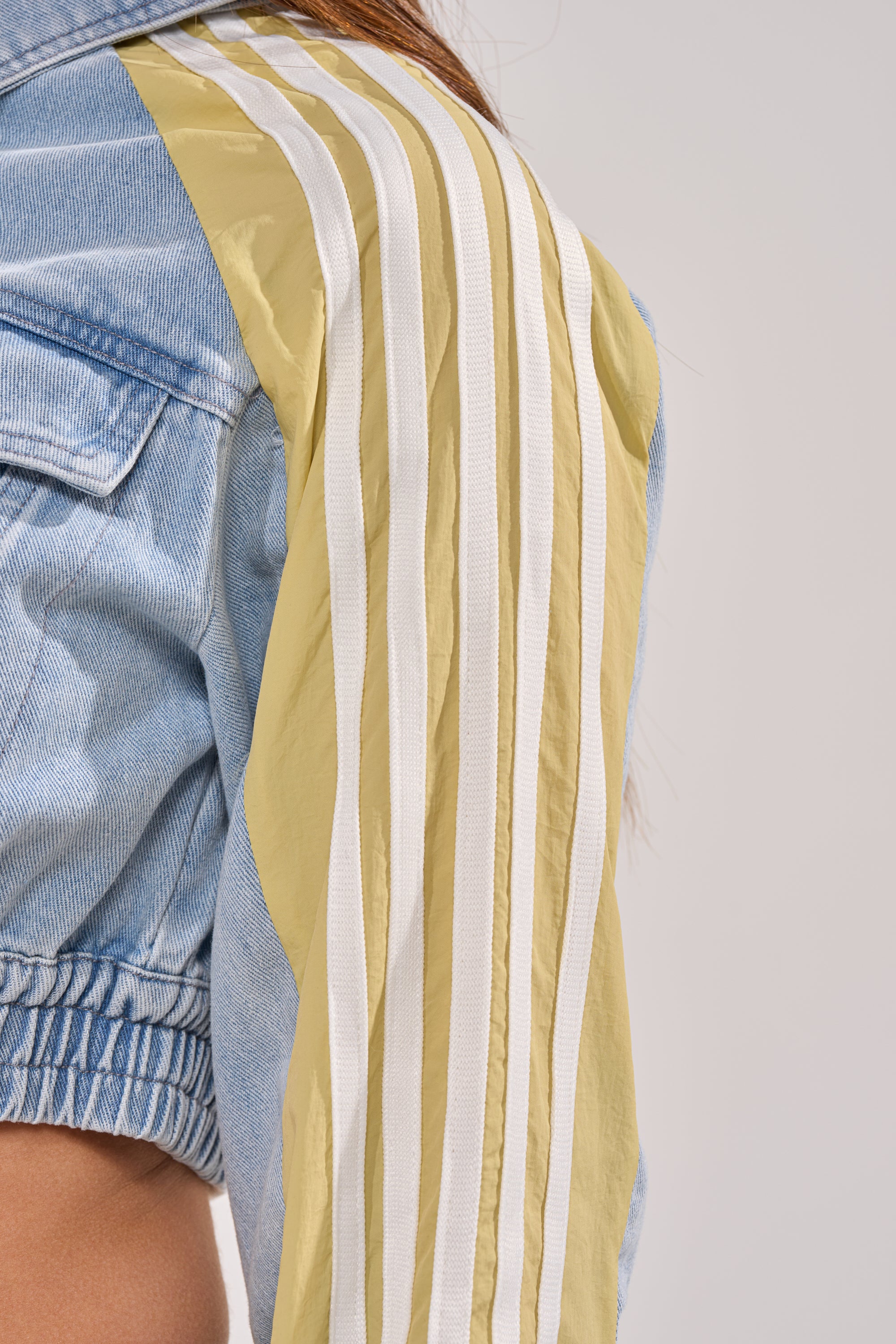 A close-up of a person wearing the NEVER BETTER DENIM JACKET, featuring yellow and white vertical sporty stripes along the shoulder and sleeve for a chic touch. 8