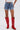 Wearing KISS MY PATCH DENIM SHORT, a white top, and tall red cowboy boots with tan embroidery, a person stands against a plain light background.
