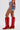 A person wears the KISS MY PATCH DENIM SHORT, featuring vintage-wash denim with embroidered details, colorful patches, and floral designs on the back, styled with knee-high red cowboy boots against a plain background.