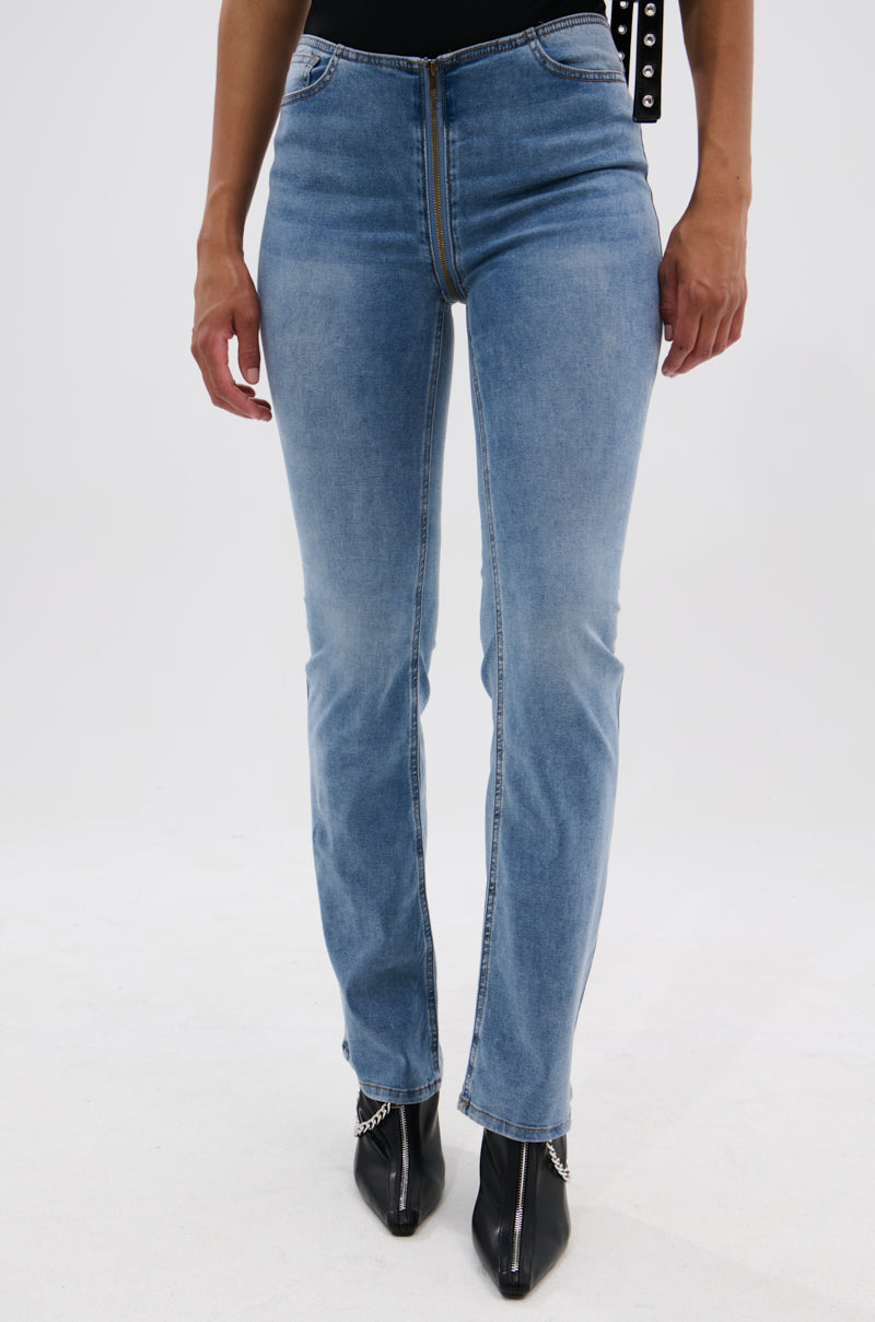 A person wearing TOO GOOD TO BE TRUE LOW RISE DENIM FLARE PANT and black pointed-toe boots with silver chains, standing against a plain white background. Only the lower torso and legs are shown.