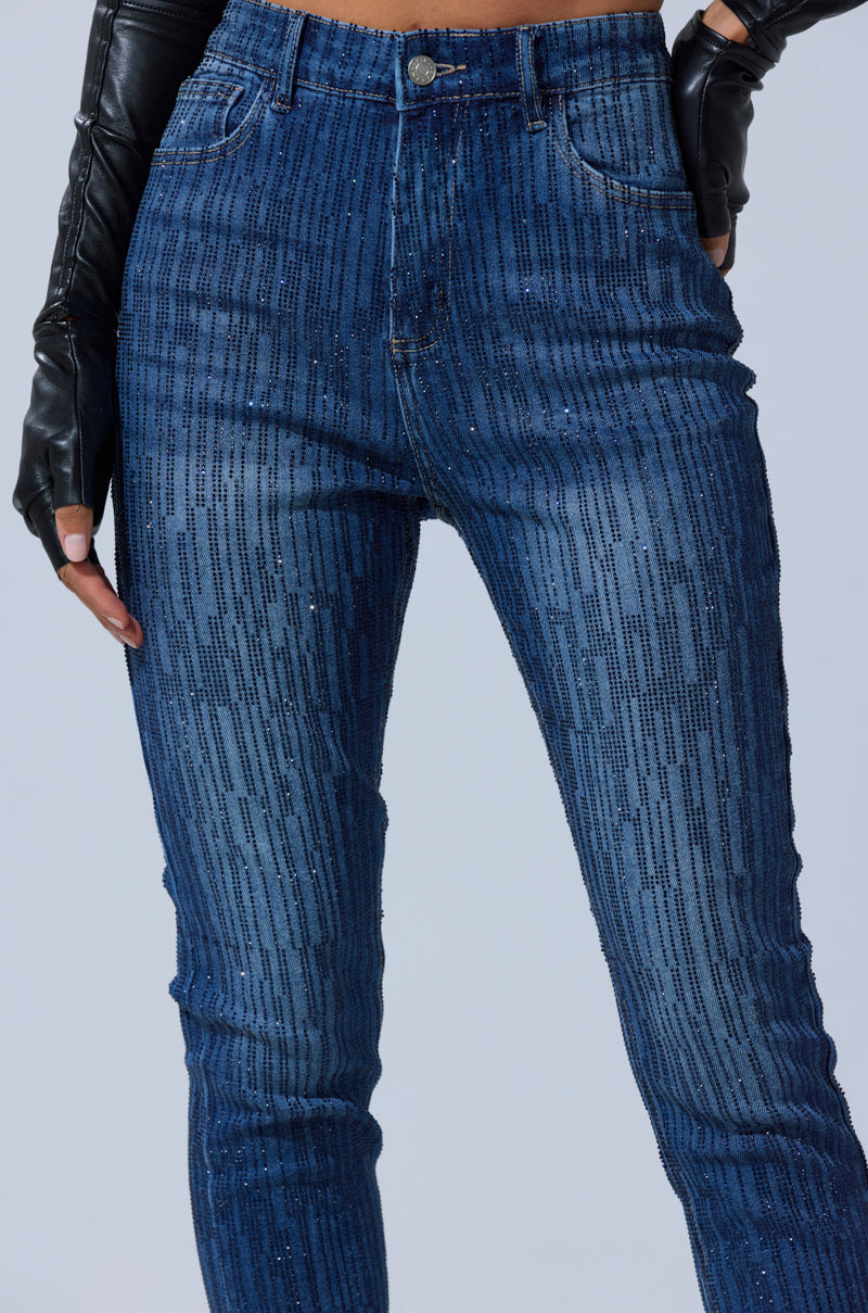A person wears the SHINING STAR RHINESTONE WIDE LEG PANT—high-rise blue denim with vertical black pinstripes—paired with black leather gloves. The waist-to-ankle photo is set against a plain light background.