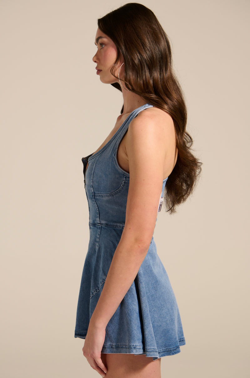 A woman with long brown hair wears the VIVIAN DENIM MINI DRESS, featuring a punk-inspired corset bodice, viewed from the side against a plain background.