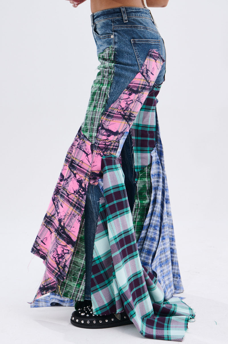 A person wearing PLAID ON PLAID DENIM JEANS with flared legs and colorful plaid and tie-dye panels in green, blue, purple, and pink stands on a white background, highlighting these bold bell-bottom jeans.