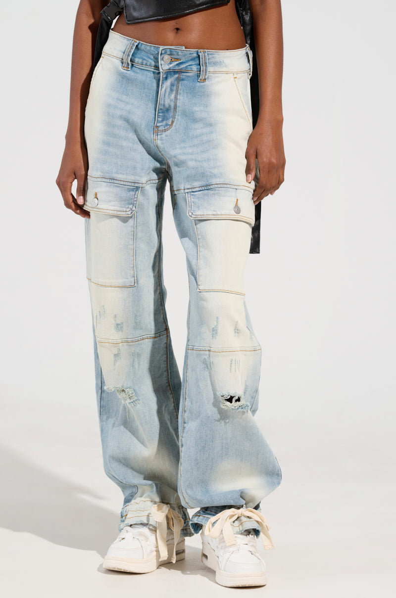 A person is wearing the "FOREVER AND A YEAR DENIM JEANS," featuring a high-rise, light blue design with a wide-leg silhouette and cargo pockets, paired with white sneakers. The focus is on the lower half of their body against a plain background.