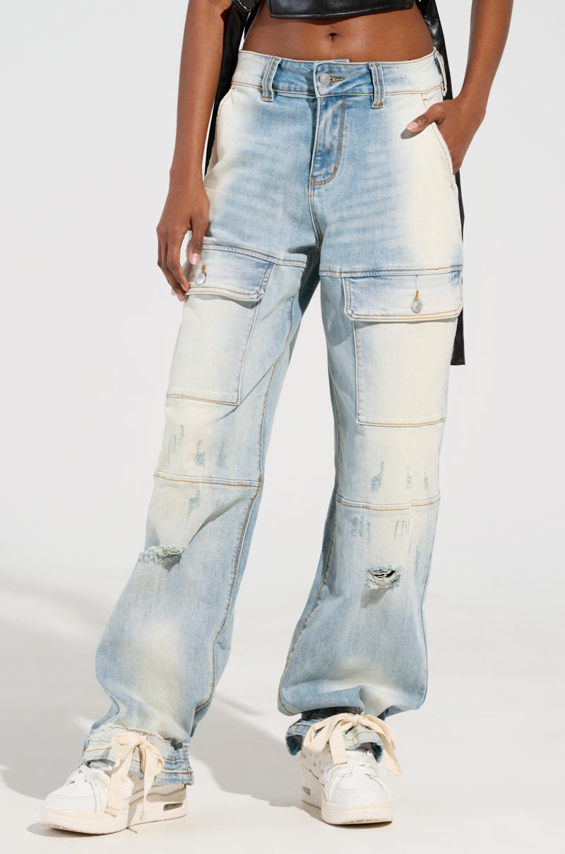 A person wearing the FOREVER AND A YEAR DENIM JEANS in light blue, featuring a distressed high-rise design and large pockets, stands against a plain background. The wide-leg silhouette complements their white sneakers perfectly. The upper part of the outfit is not visible in the frame.