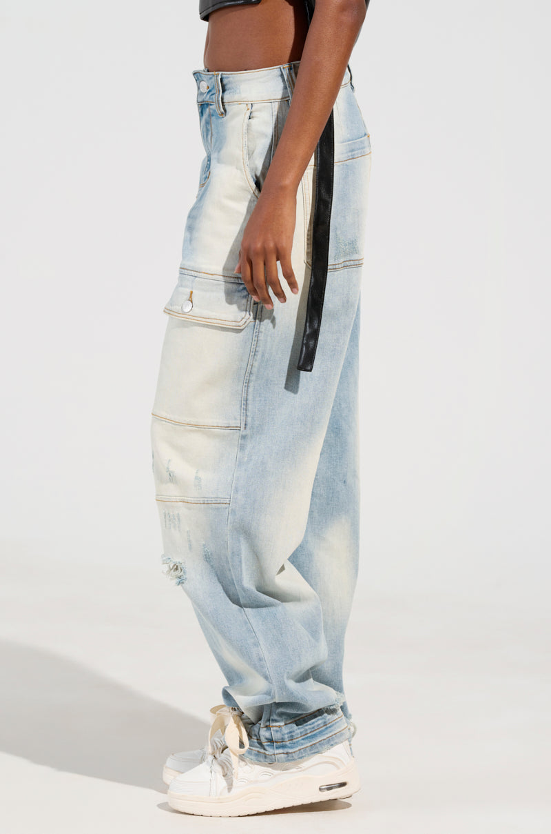 A person wearing FOREVER AND A YEAR DENIM JEANS in light blue with a wide-leg silhouette and large pockets, complemented by white sneakers and a black belt hanging from the side. The high-rise design enhances their faded, vintage appearance against a plain, light-colored background.
