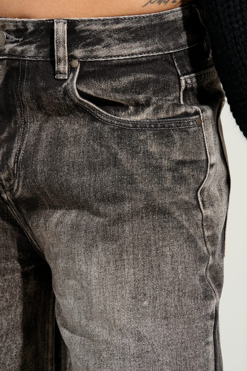 Close-up of a person wearing the LITERAL PERFECTION BLACK DENIM BERMUDA SHORTS, featuring a high-rise design. The texture of the denim is visible, and there is a glimpse of a dark sweater at the top of the image. 11