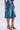 Someone wears LITERAL PERFECTION BLUE DENIM BERMUDA SHORTS with a frayed hem and baggy fit, styled with open-toe animal print high-heeled sandals. The high-rise denim stands out against a simple light background.