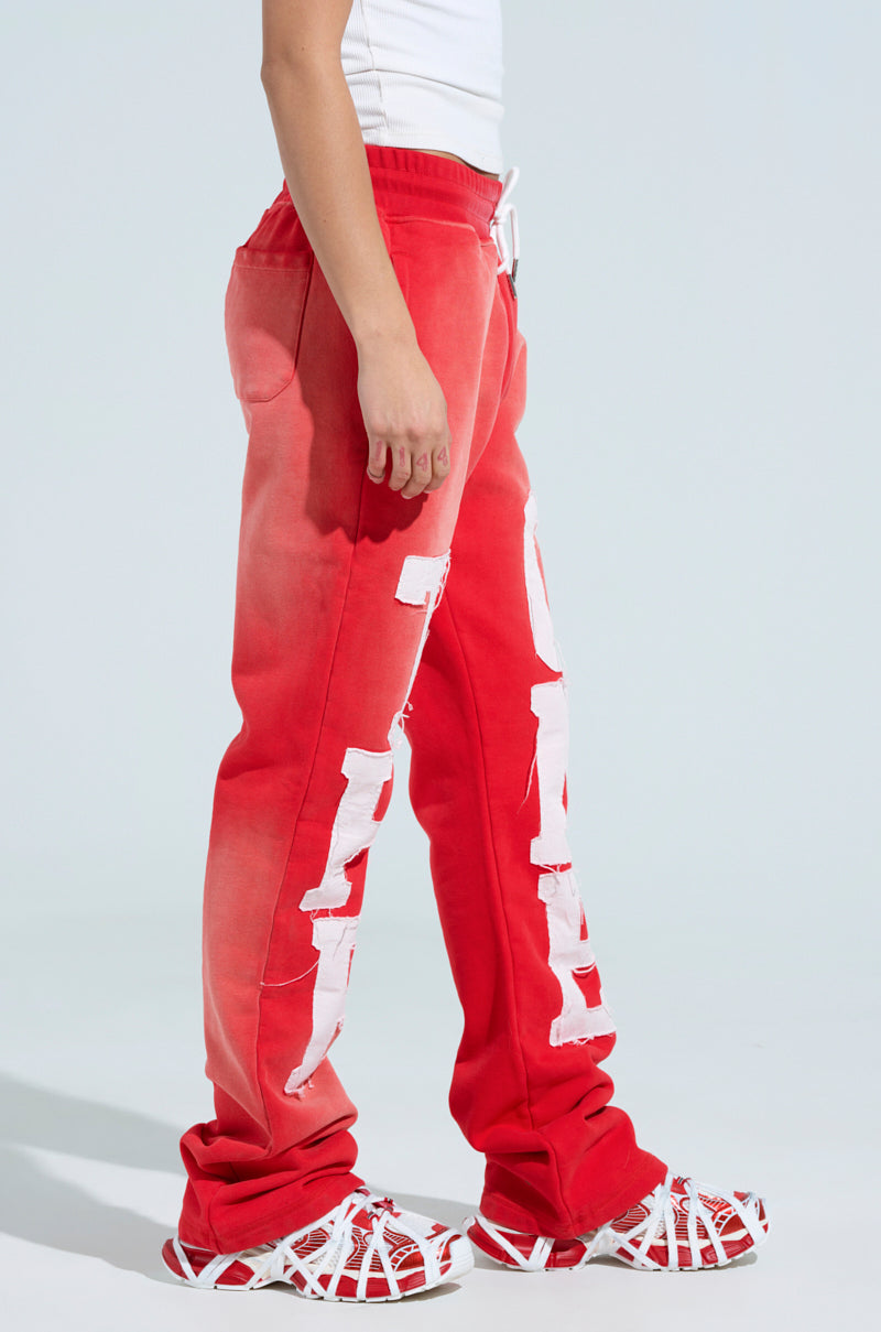 Wearing vibrant red ONLY ONE WIDE LEG PANT with elastic waistband and bold white lettering, paired with a crisp white shirt and matching red and white sneakers, a person stands in side profile against a plain background. 3