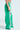 Sporting the JUMP AROUND WIDE LEG JOGGER IN GREEN with white side stripes and a smiley face patch, these high-rise pants feature an elastic waistband and pair perfectly with white shoes for a chic athleisure look.