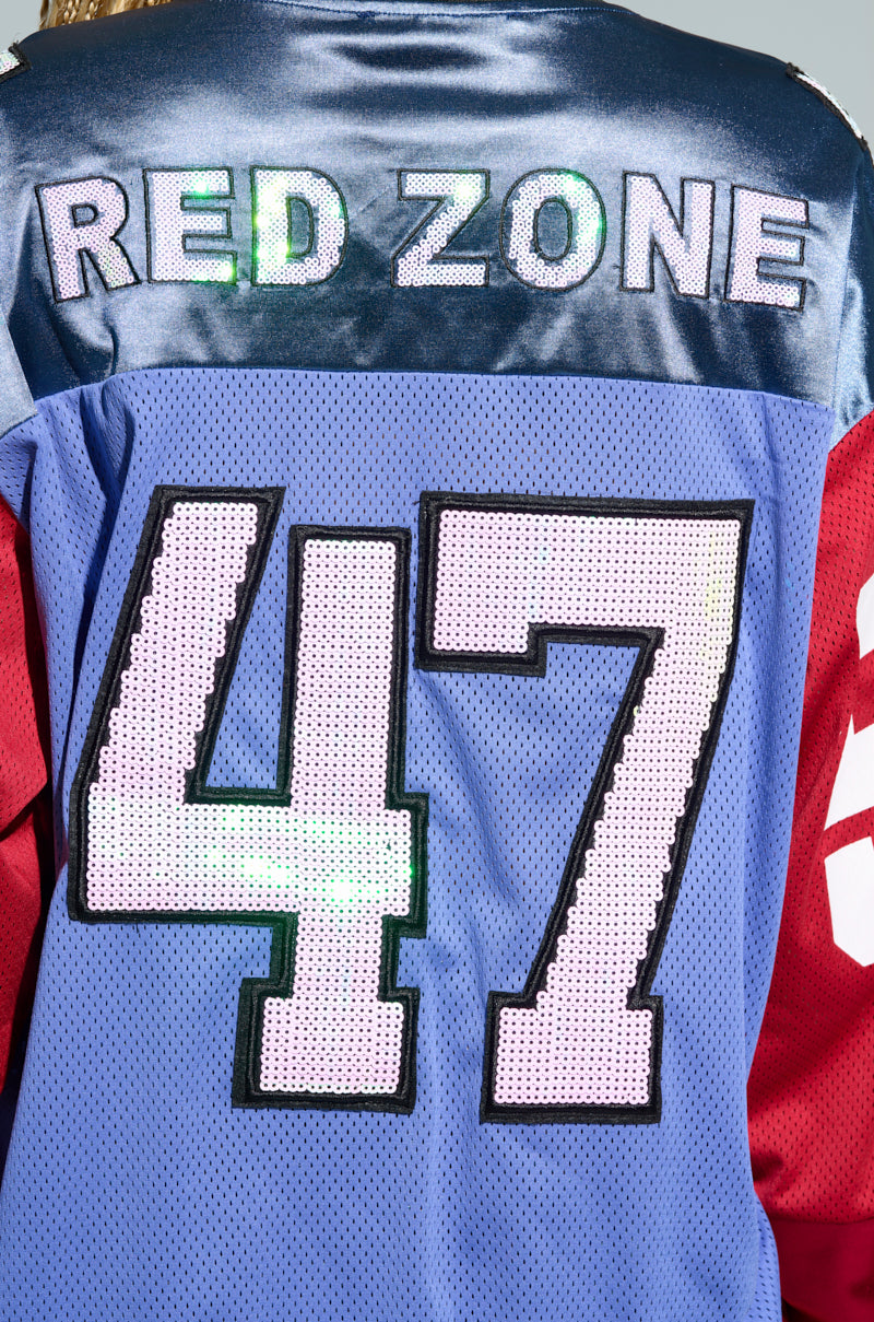 The back of the GAME TIME JERSEY displays "RED ZONE" prominently in bold letters above the number "47." This jersey boasts an oversized silhouette with a striking color block pattern, featuring a predominantly blue body and vibrant red sleeves. 8