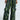 Person wearing the RUNNIN WILD CARGO PANT in a sleek green and black snakeskin pattern, featuring multiple pockets and button details. These faux leather pants boast a shiny, textured surface for a bold look.