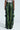 Back view of a person wearing the RUNNIN WILD CARGO PANT, designed with green snake-print in faux leather. The pants feature a loose fit, multiple pockets, and a shiny texture. Set against a plain, light background, the unique snakeskin pattern is prominently highlighted.
