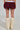 The image shows a person from behind, wearing the Varsity Squad Bubble Mini Skirt in burgundy with its unique bubble hem and fluffy off-white boots.