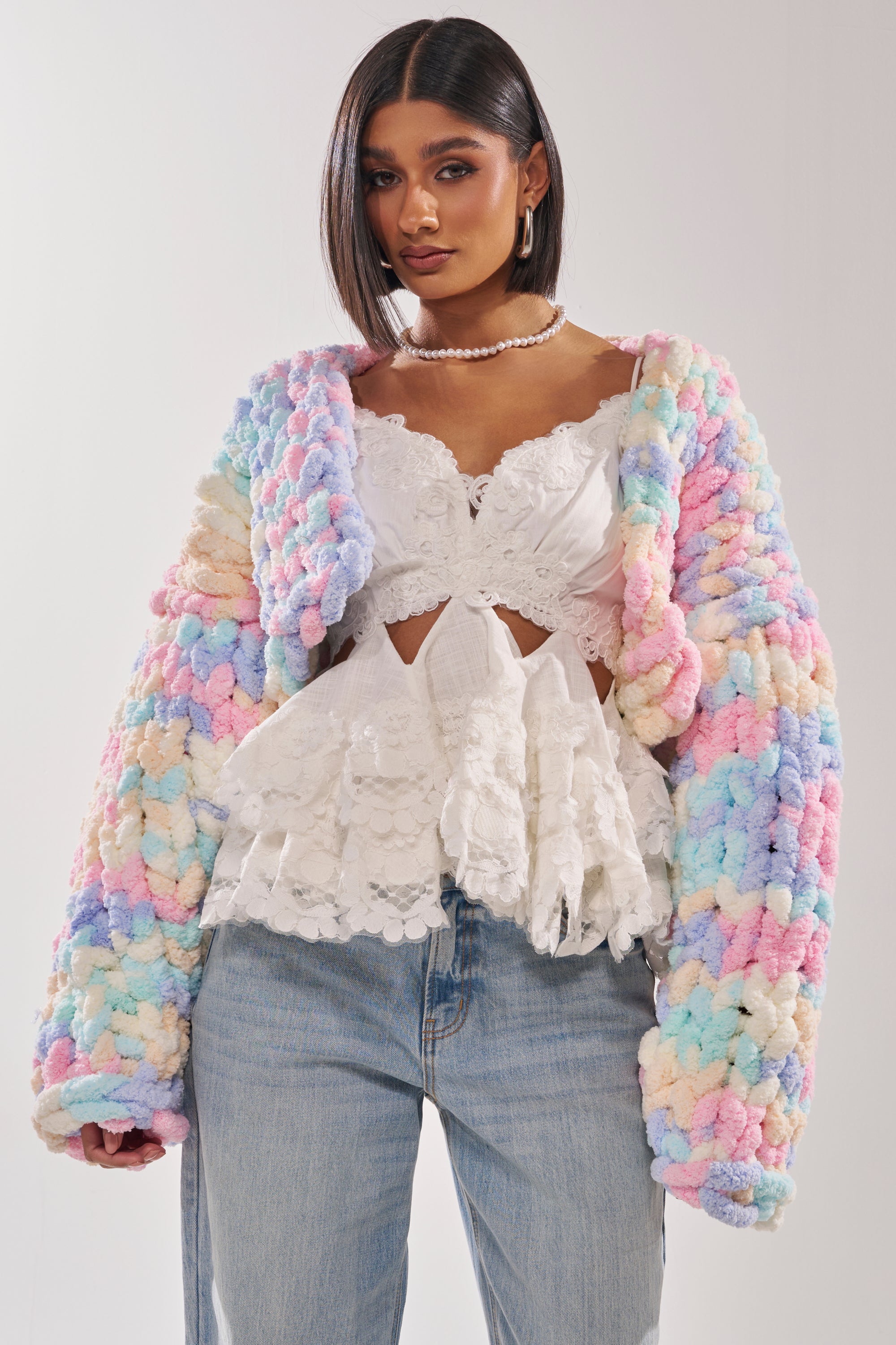 A woman in a white top and the ALIA CHUNKY CHENILLE KNIT CARDIGAN. 0