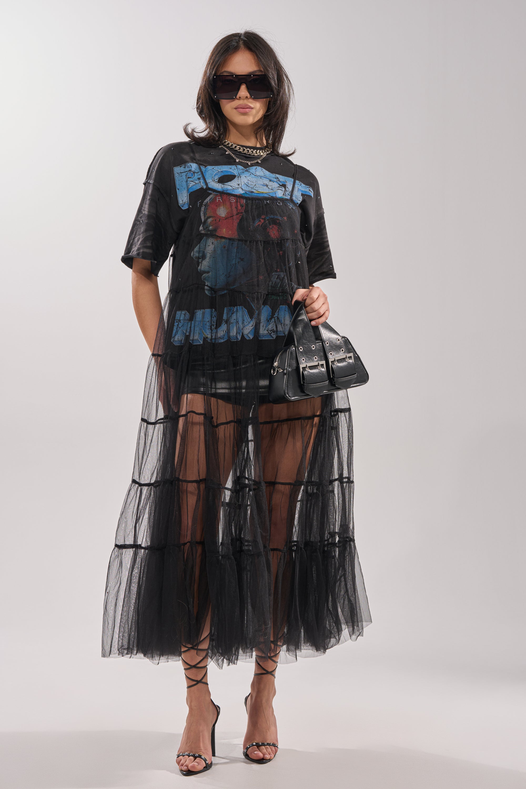A woman wears the PERFECT FOR LAYERING TULLE MAXI DRESS over a graphic T-shirt dress, styled with sunglasses, strappy heels, and a black handbag, standing against a plain light background. 5