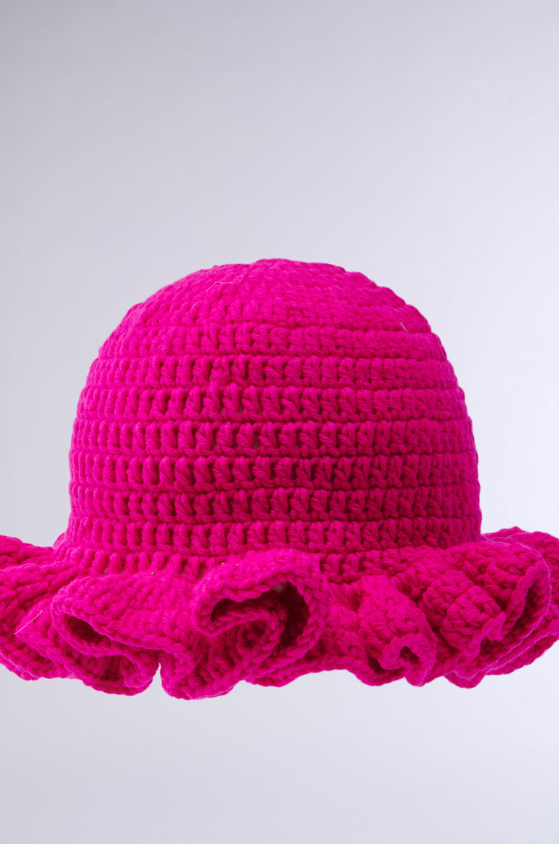 The CROCHET NIGHTS HAT, in bright pink with a wide ruffled brim and crochet knit design, is shown against a plain light gray background.